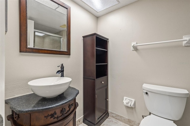 bathroom with a shower with shower door, vanity, and toilet