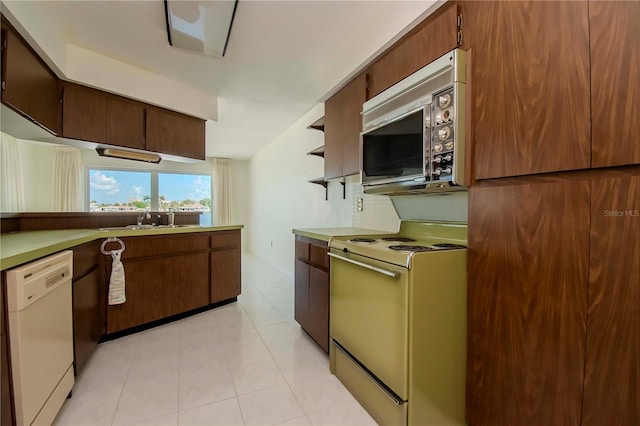 kitchen featuring light tile patterned flooring, stove, dishwasher, and sink