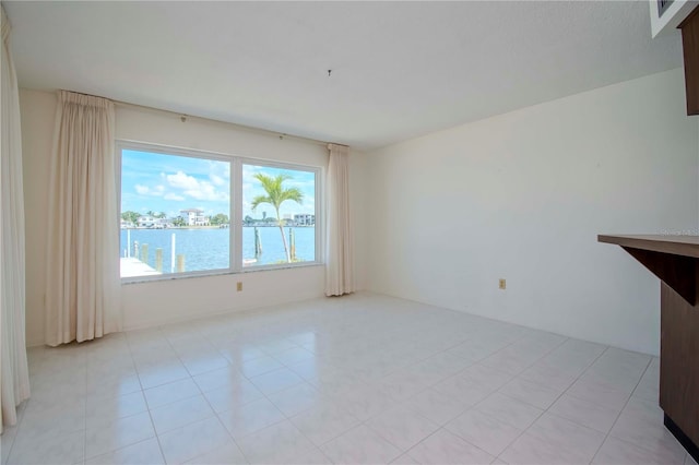 tiled empty room featuring a water view and a wealth of natural light