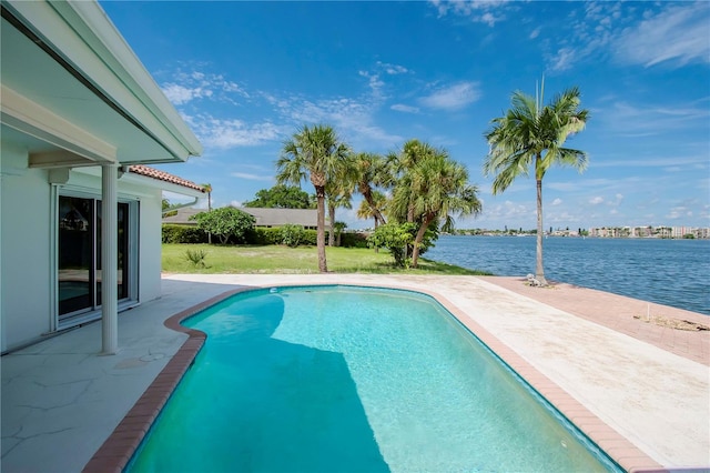 view of pool featuring a water view, a patio area, and a yard