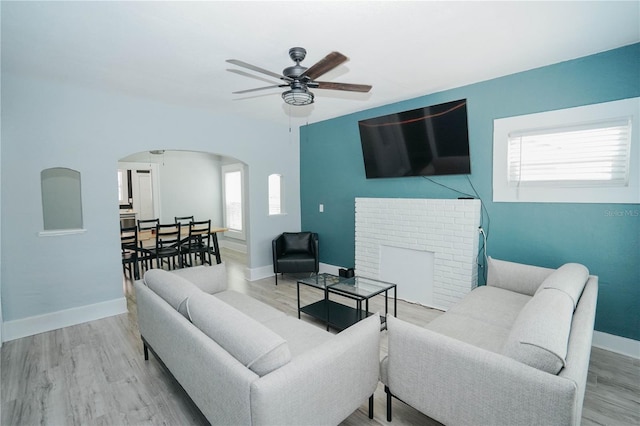 living room featuring ceiling fan, light hardwood / wood-style floors, and a fireplace