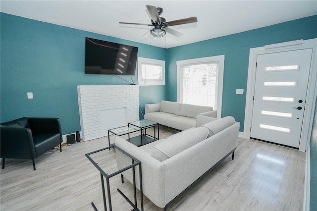 living room featuring ceiling fan, a fireplace, and light hardwood / wood-style flooring