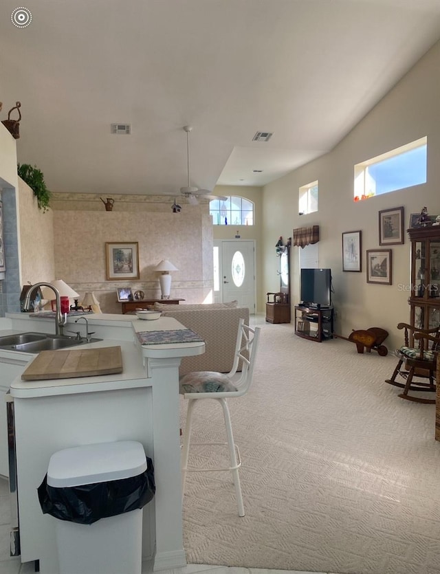 kitchen with sink, kitchen peninsula, a kitchen breakfast bar, and light colored carpet