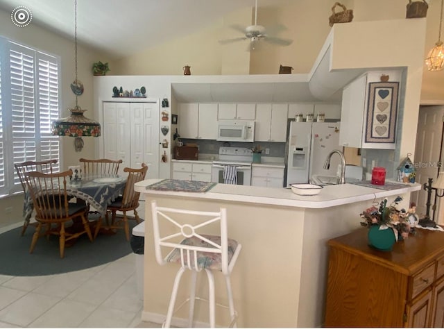 kitchen with light tile patterned flooring, ceiling fan, hanging light fixtures, white appliances, and lofted ceiling