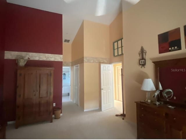 carpeted bedroom with high vaulted ceiling