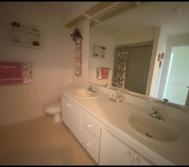 bathroom featuring toilet and double sink vanity