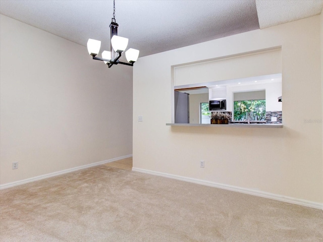 unfurnished room with carpet, a textured ceiling, and a chandelier