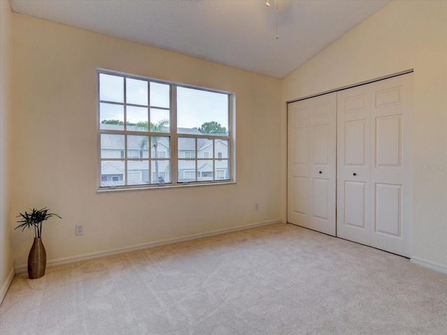 unfurnished bedroom featuring a closet, lofted ceiling, and light colored carpet