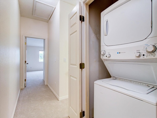 laundry room featuring light colored carpet, a textured ceiling, and stacked washer / drying machine