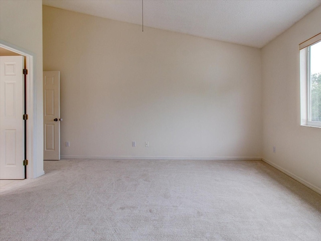 spare room featuring light carpet and vaulted ceiling