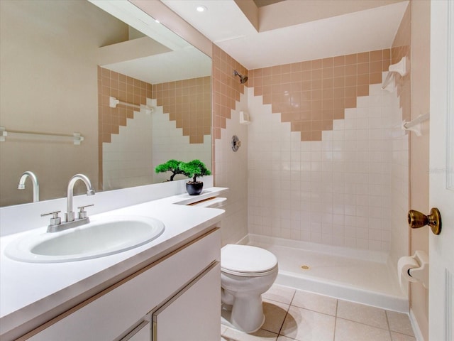 bathroom with vanity, tiled shower, toilet, and tile patterned flooring