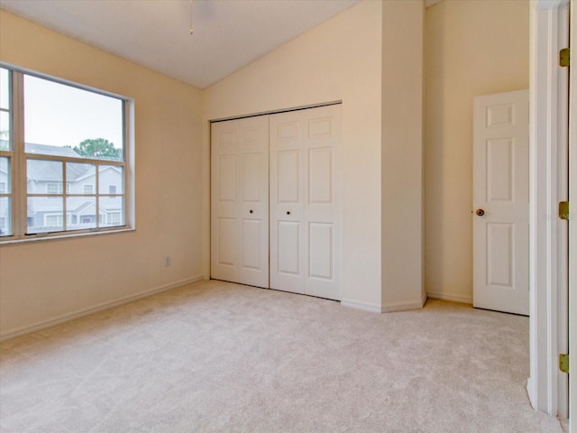 unfurnished bedroom with a closet, vaulted ceiling, and light colored carpet