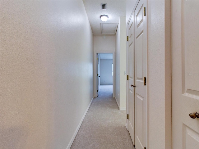 hallway featuring a textured ceiling and light colored carpet