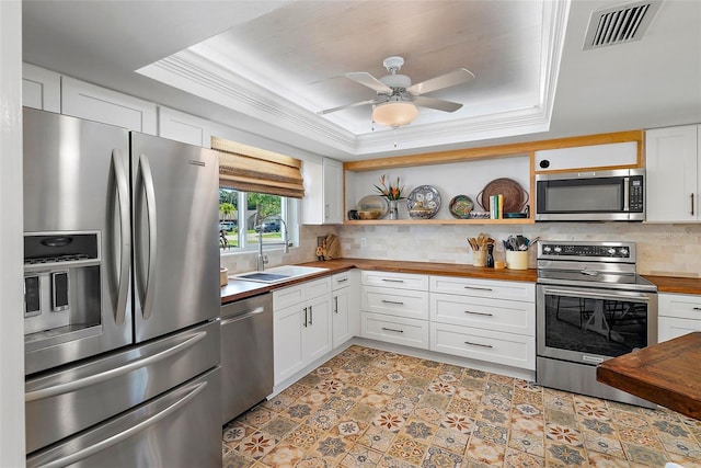 kitchen with sink, white cabinetry, a tray ceiling, and stainless steel appliances