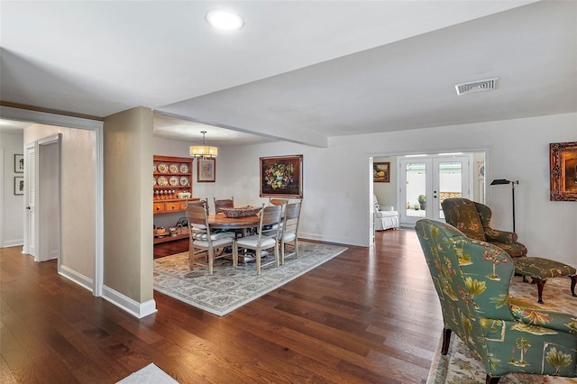 dining space featuring dark hardwood / wood-style flooring, french doors, and an inviting chandelier