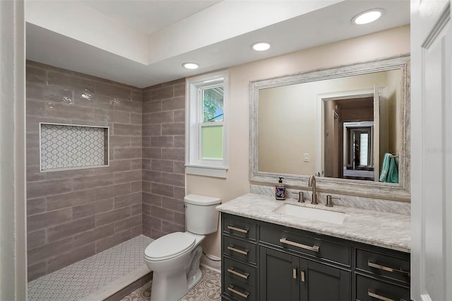 bathroom featuring toilet, vanity, and a tile shower