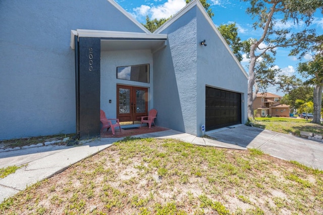 view of front of property with french doors, a garage, and a front lawn