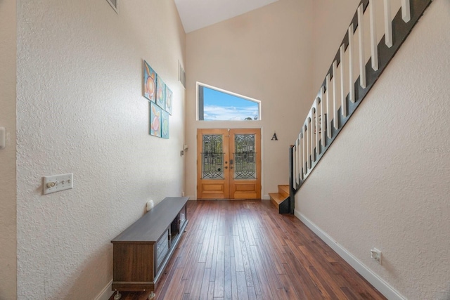 entryway with a towering ceiling, dark wood-type flooring, and french doors