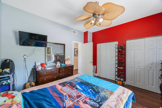 bedroom featuring multiple closets, dark hardwood / wood-style floors, and ceiling fan