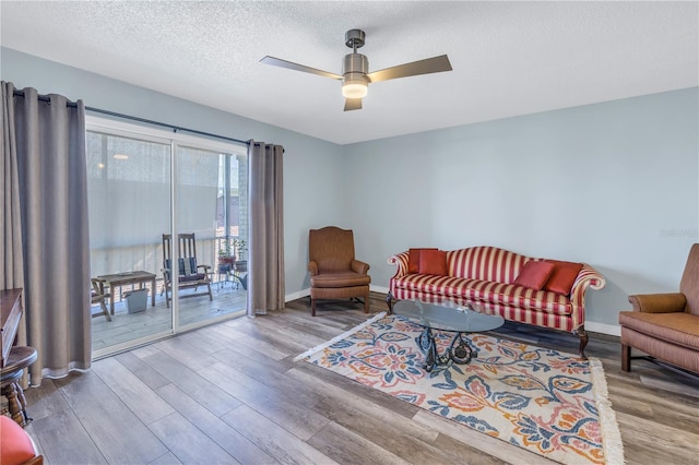 living room with ceiling fan, a textured ceiling, and light hardwood / wood-style flooring