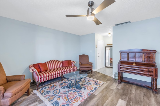 living room featuring a textured ceiling, light hardwood / wood-style flooring, and ceiling fan