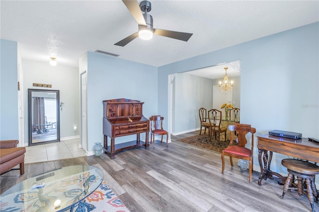 living area featuring a textured ceiling, ceiling fan with notable chandelier, and hardwood / wood-style flooring