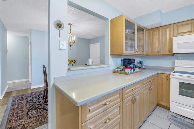 kitchen with a notable chandelier, white appliances, a textured ceiling, and hanging light fixtures