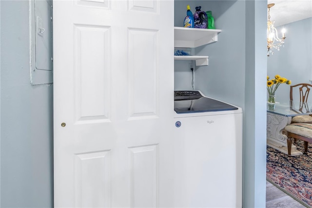 clothes washing area with hardwood / wood-style flooring, a notable chandelier, and washer / dryer