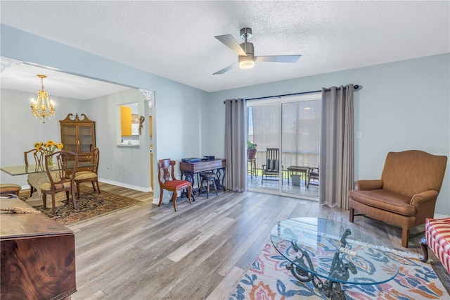 living room featuring a textured ceiling, light hardwood / wood-style floors, and ceiling fan with notable chandelier