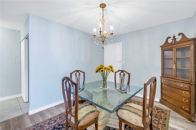 dining area with a chandelier, a textured ceiling, and light hardwood / wood-style flooring