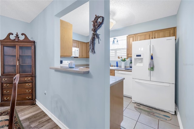 kitchen with a textured ceiling, light hardwood / wood-style floors, and white appliances