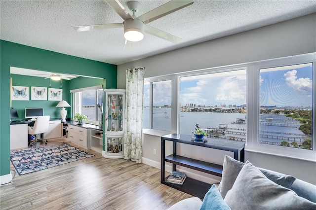 office with a water view, ceiling fan, a textured ceiling, and light hardwood / wood-style floors