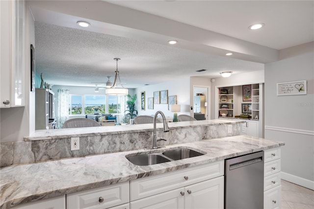 kitchen with sink, white cabinetry, hanging light fixtures, dishwashing machine, and light stone counters