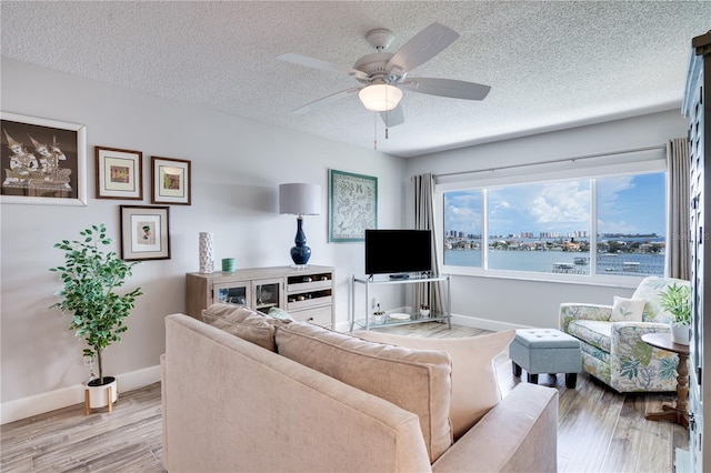 living room featuring a textured ceiling, ceiling fan, and hardwood / wood-style flooring