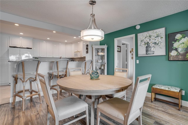 dining room with a textured ceiling and light hardwood / wood-style flooring