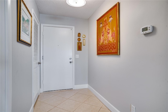 doorway with a textured ceiling and light tile patterned floors