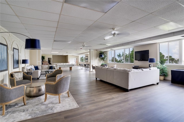 living room with hardwood / wood-style flooring, plenty of natural light, a drop ceiling, and ceiling fan