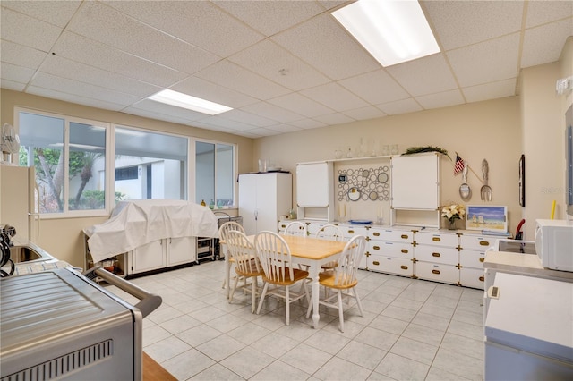 tiled dining area featuring a drop ceiling