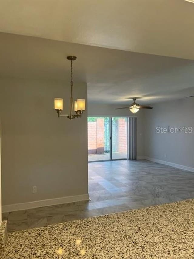 spare room with ceiling fan with notable chandelier