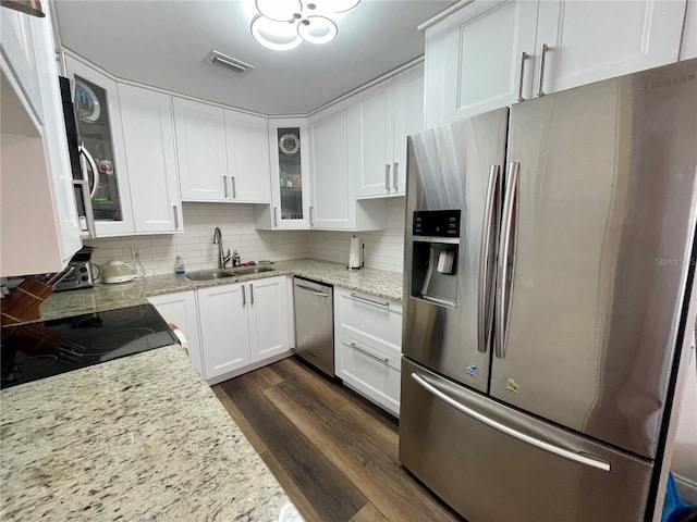 kitchen featuring appliances with stainless steel finishes, sink, backsplash, dark hardwood / wood-style floors, and light stone countertops