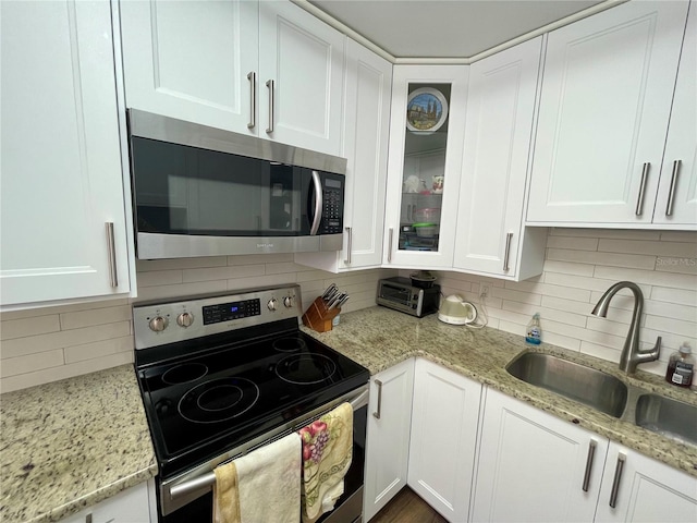 kitchen with sink, white cabinets, decorative backsplash, and stainless steel appliances