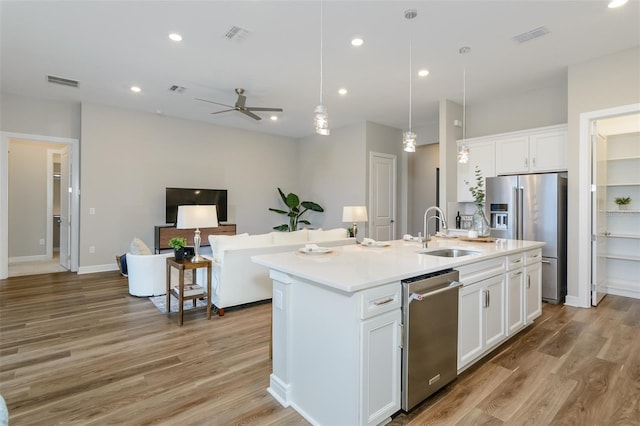 kitchen featuring white cabinetry, sink, stainless steel appliances, and a kitchen island with sink