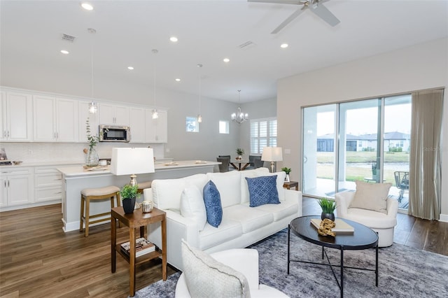 living room featuring ceiling fan with notable chandelier and dark hardwood / wood-style floors