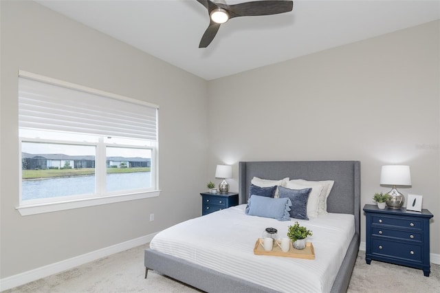 bedroom with ceiling fan, light carpet, and a water view