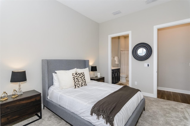 bedroom with light colored carpet and ensuite bath