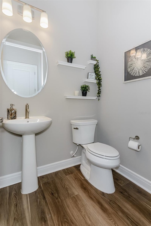 bathroom featuring toilet, wood-type flooring, and sink