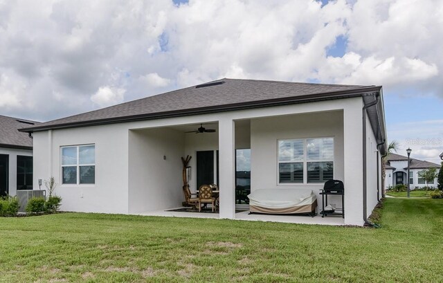 rear view of house with ceiling fan, a patio area, and a yard