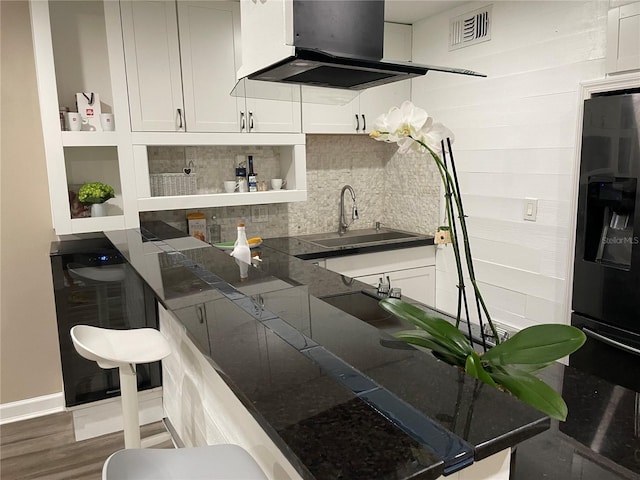 kitchen with white cabinets, dark hardwood / wood-style flooring, sink, stainless steel fridge, and range hood