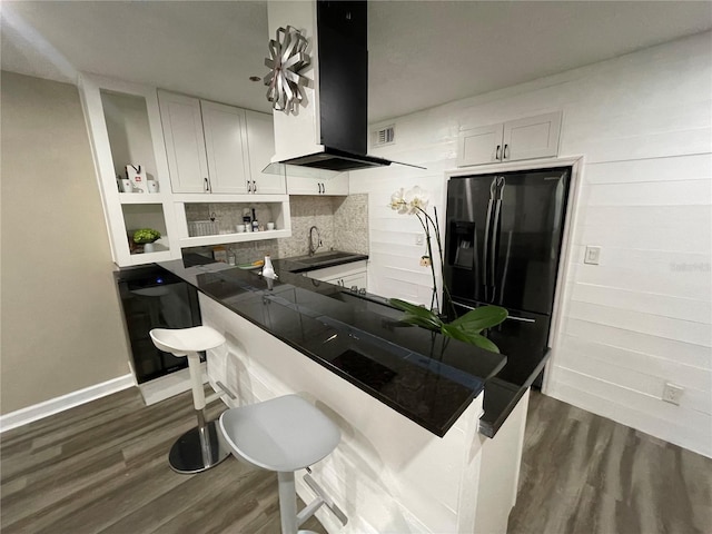 kitchen featuring kitchen peninsula, sink, extractor fan, white cabinetry, and black refrigerator with ice dispenser