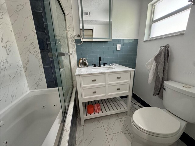 full bathroom featuring vanity, toilet, a textured ceiling, and tiled shower / bath combo